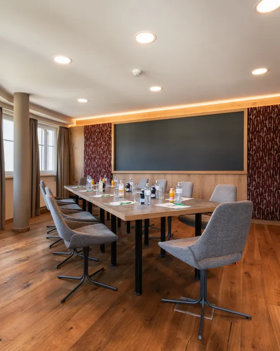 Moderna sala conferenze con pavimento in legno, grande tavolo, sedie e bevande in bottiglia