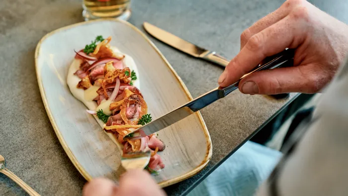 Gourmet roast beef dish with onion, parsley, and creamy sauce on a ceramic plate