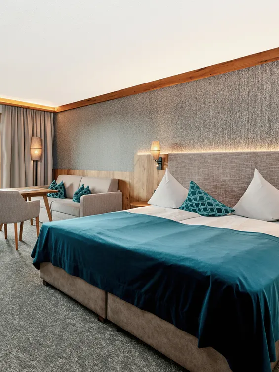 Moderna camera d'albergo con letto matrimoniale, area salotto e accesso al balcone