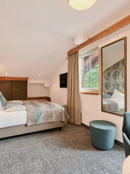 Modernes Hotelzimmer mit Doppelbett, gemusterter Tapete, Balkonzugang und natürlichem Licht