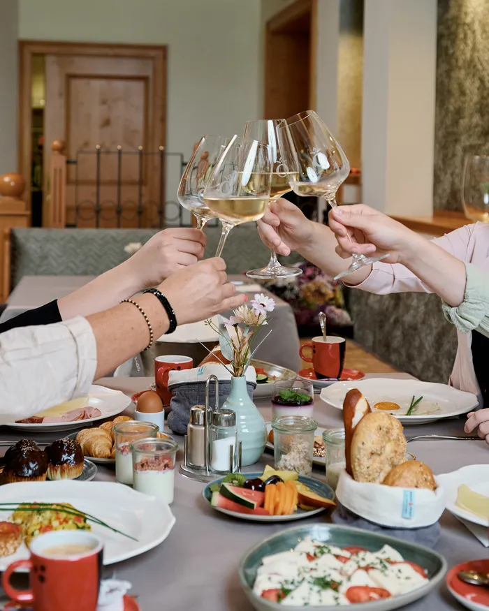 Vier Frauen stoßen beim gemütlichen Frühstück mit Weißwein an