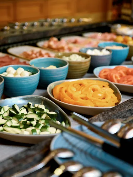 Ricco buffet per colazione con verdure fresche, formaggi e salumi in ciotole di ceramica