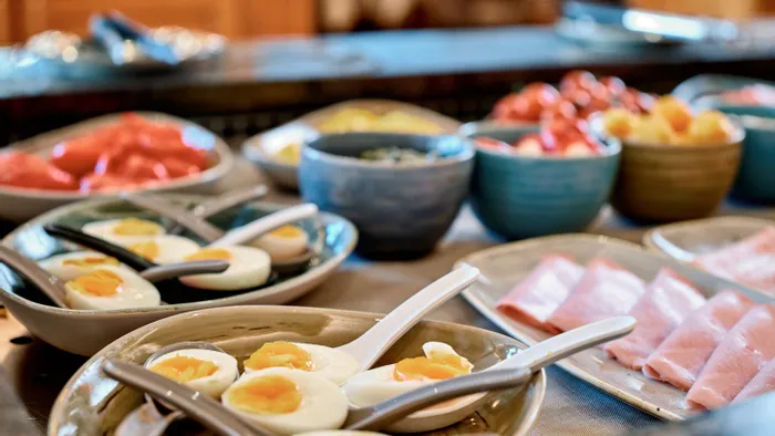 Breakfast buffet with soft-boiled eggs, sliced ham, and assorted fresh ingredients