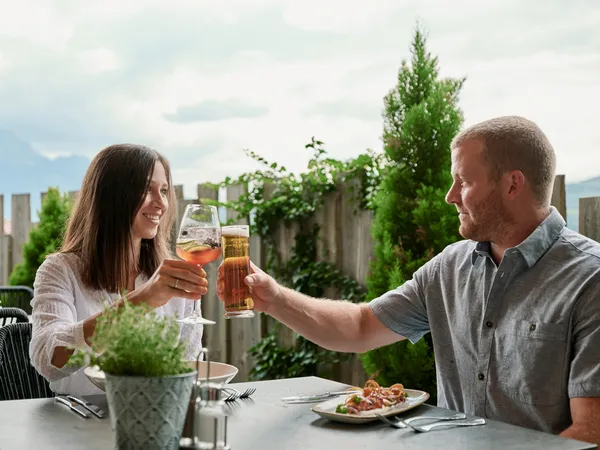 Paar prostet sich mit Bier und Cocktail an einem Tisch im Freien zu