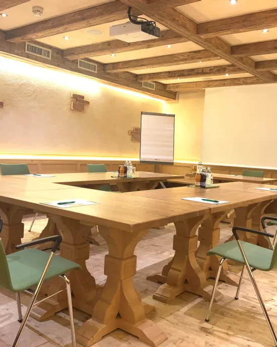 Moderner Besprechungsraum im rustikalen Stil mit Holztischen, grünen Stühlen und Präsentationsausstattung