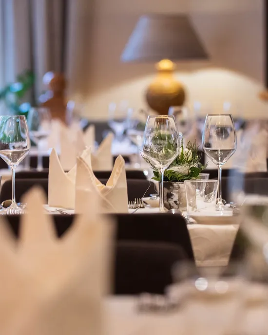 Elegante Restauranttischdekoration mit Weingläsern, gefalteten Servietten und sanfter Beleuchtung