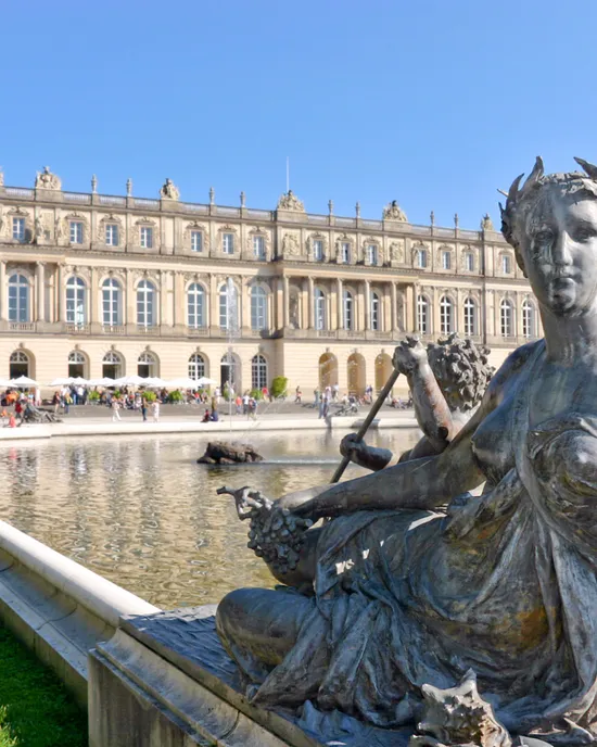 Statua in bronzo nella fontana davanti al Palazzo di Herrenchiemsee con turisti sullo sfondo