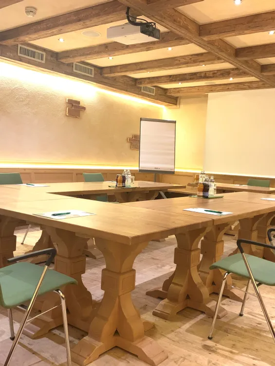 Moderner Besprechungsraum im rustikalen Stil mit Holztischen, grünen Stühlen und Präsentationsausstattung