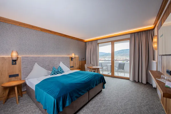 Modernes Hotelzimmer mit Doppelbett, Balkonblick und Berglandschaft
