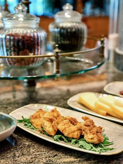 Assorted antipasti with cheese slices, breaded fried bites, and fresh soft cheese on dining table