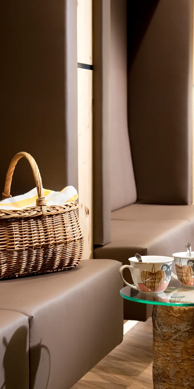 Gemütliche Lounge mit Picknickkorb, Teetassen auf rustikalen Holz- und Glastischen