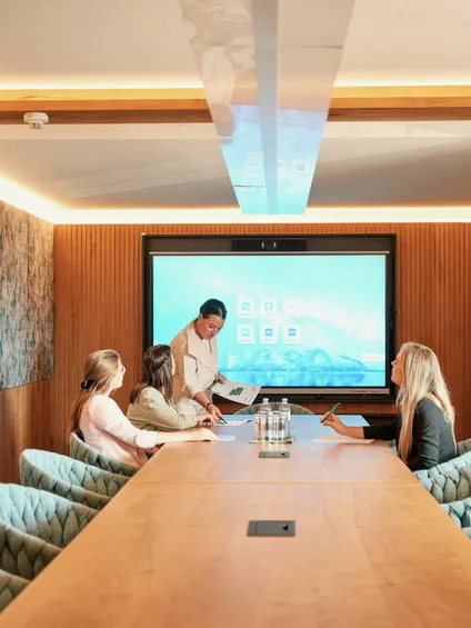 Business meeting in modern conference room with digital presentation screen and wood accents