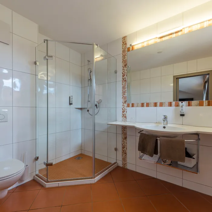 Modernes Bad mit Glasdusche, Waschbecken und wandmontierter Toilette, geflieste Wände und Boden