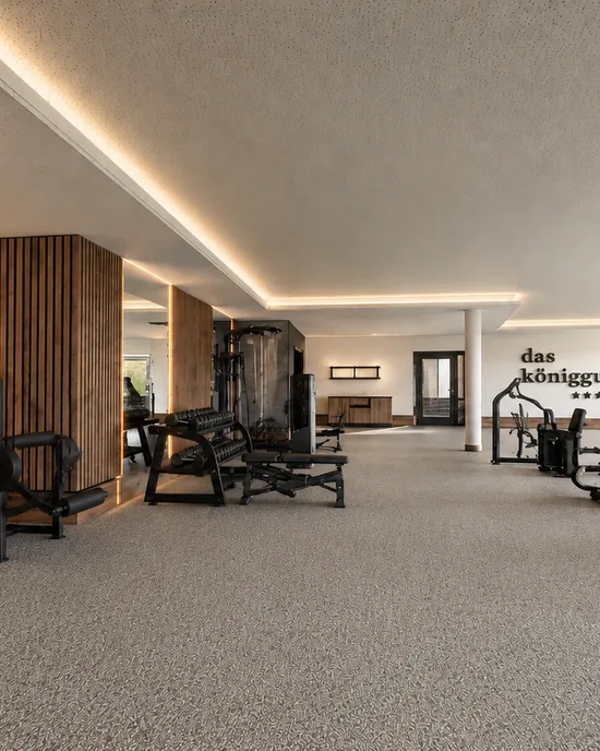 Moderner Fitnessraum mit Trainingsgeräten und Hantelbänken