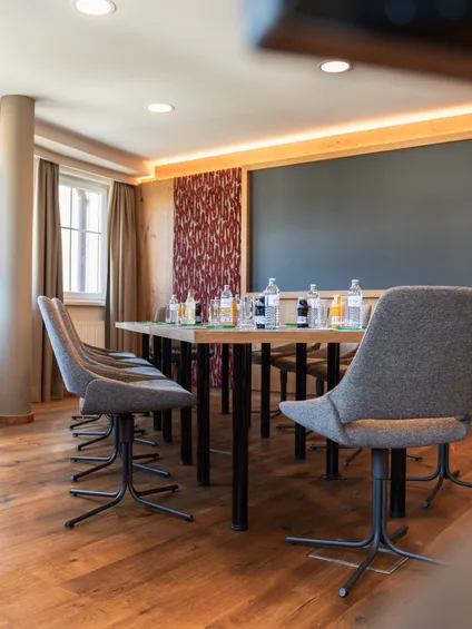 Modern conference room with wooden floor, grey chairs, and drinks on the meeting table