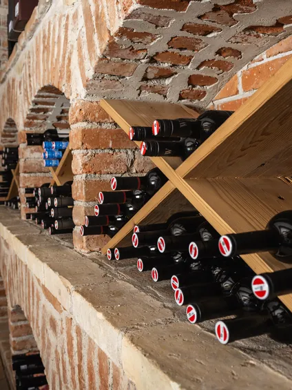 Weinflaschen lagern im Backsteinkeller auf Holzregalen