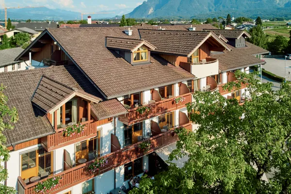 Traditionelles Alpenhotel mit Blumenbalkonen und Bergblick im Sommer