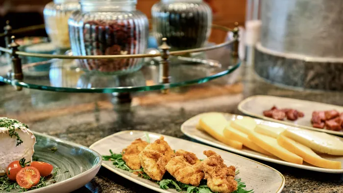Assorted antipasti with cheese slices, breaded fried bites, and fresh soft cheese on dining table