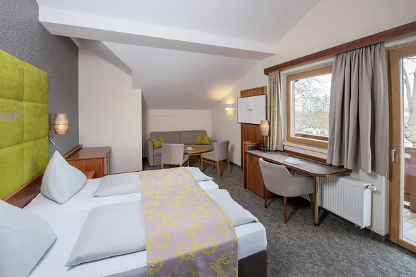 Cozy hotel room with double bed, seating area, desk and balcony view