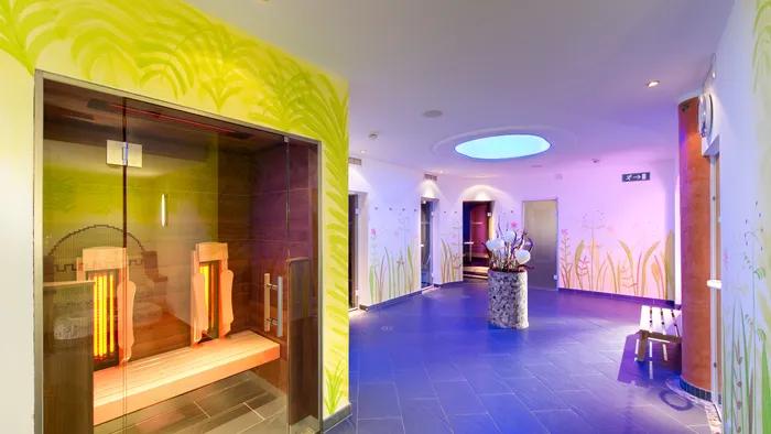 Modern spa wellness area with infrared sauna, floral wall decor and ambient lighting