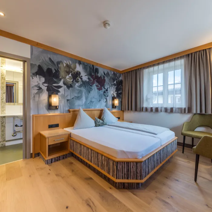 Modernes Hotelzimmer mit Doppelbett, Blumenwandbild und Holzmöbeln