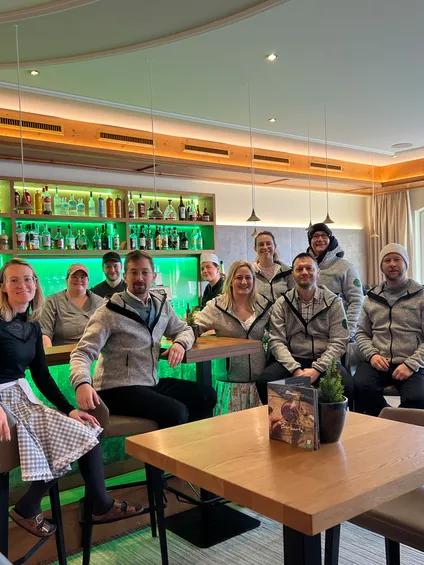 Gruppe von Restaurantmitarbeitern in einheitlicher Kleidung an moderner Bar mit grüner Beleuchtung