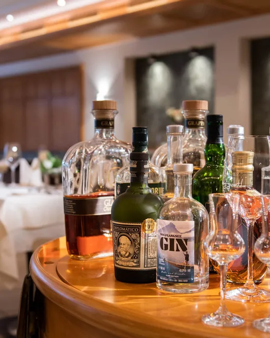 Verschiedene Spirituosenflaschen und Cocktailgläser auf einem Servierwagen in einem gehobenen Restaurant