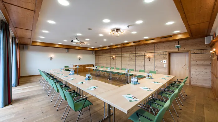 Modern conference room with U-shaped table, green chairs, and wooden interior