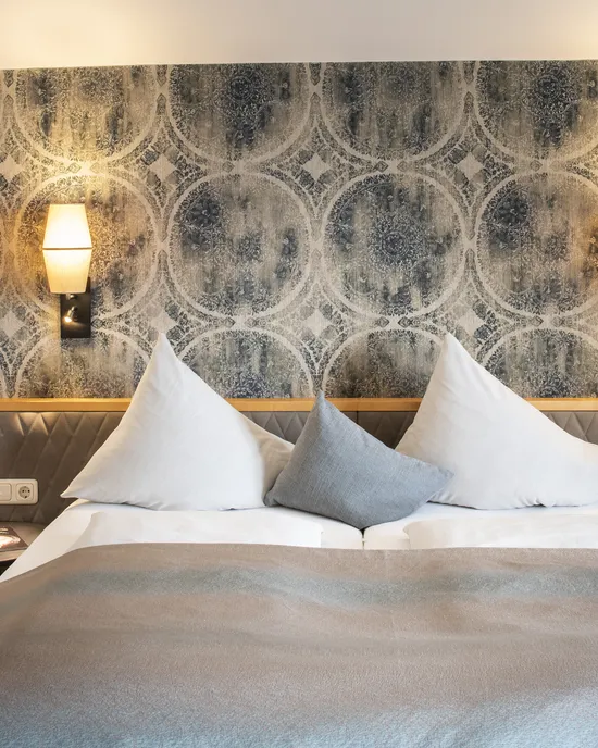Modern hotel room with double bed, geometric wallpaper and soft lighting