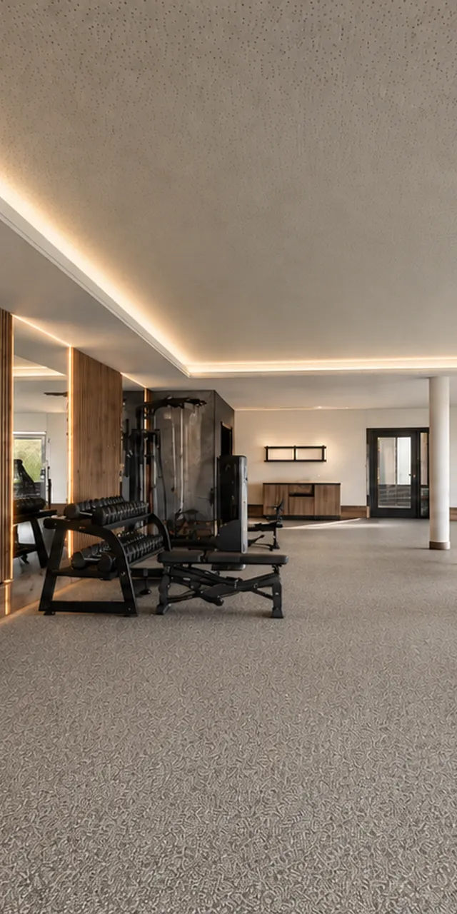 Moderner Fitnessraum mit Trainingsgeräten und Hantelbänken
