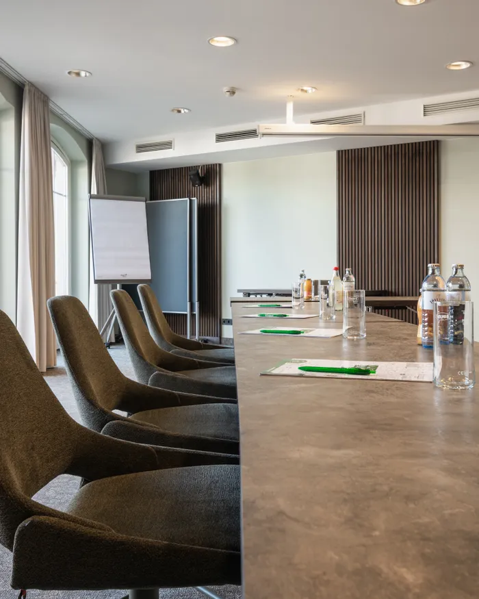 Modern conference room with long table, office chairs, notepads and water bottles
