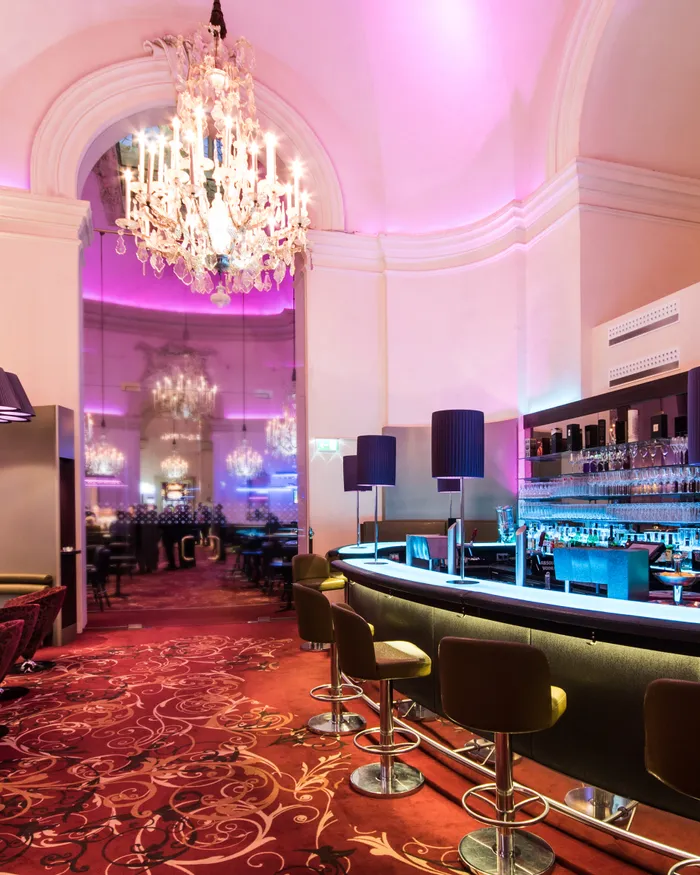 Modern cocktail bar with chandelier lighting and purple ambient decor
