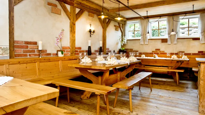 Rustic wooden restaurant interior with long tables set with glasses and folded napkins