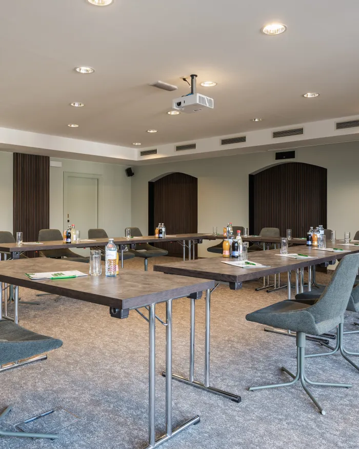 Sala conferenze moderna con tavoli a U, sedie e bevande pronte per una riunione di lavoro