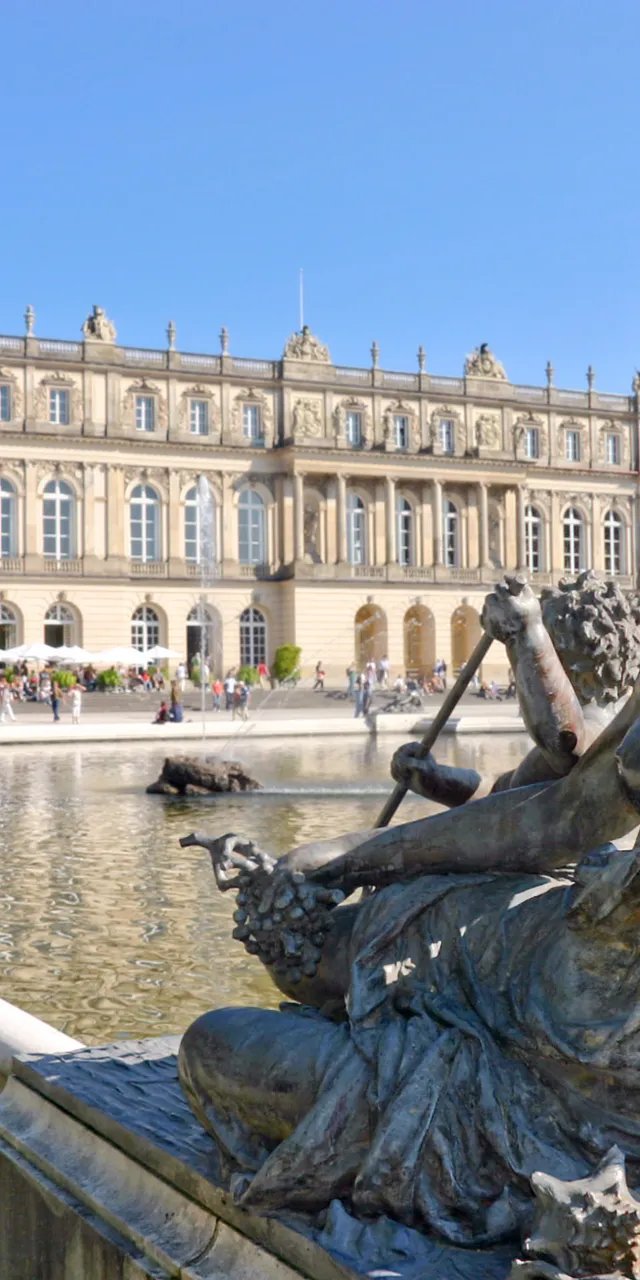 Statua in bronzo nella fontana davanti al Palazzo di Herrenchiemsee con turisti sullo sfondo