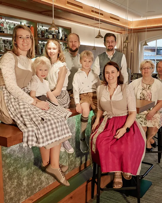 Familie in traditioneller Alpenkleidung posiert gemeinsam in modernem Barbereich