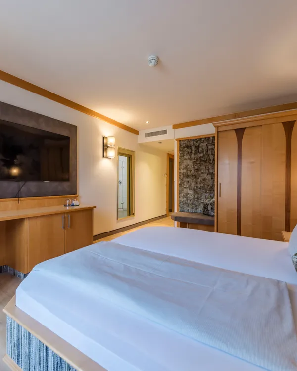 Modernes Hotelzimmer mit Holzmöbeln, großem Bett und Flachbildfernseher