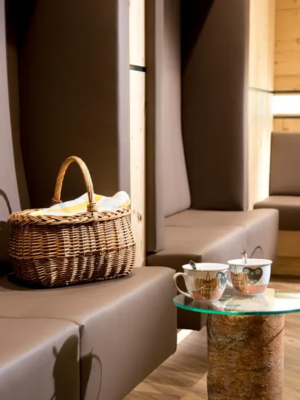 Cozy lounge with wicker basket, tea cups on rustic wood and glass tables