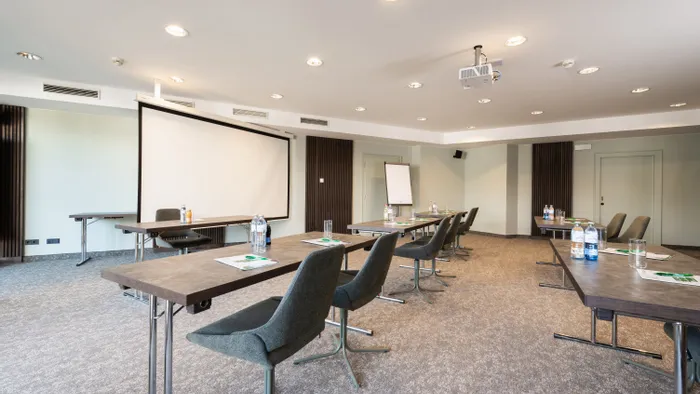 Moderner Konferenzraum mit Beamer, Besprechungstischen, Wasserflaschen und Notizblöcken