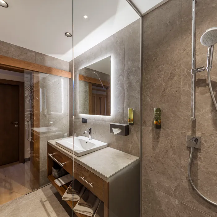 Modernes Badezimmer mit Steinen, beleuchtetem Spiegel und begehbarer Dusche