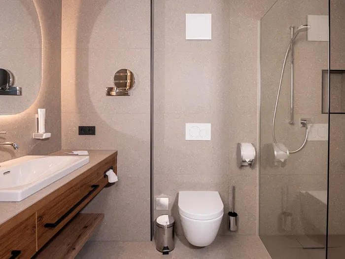 Modernes Hotelbad mit begehbarer Dusche, wandhängendem WC und Holzwaschtisch mit breitem Waschbecken