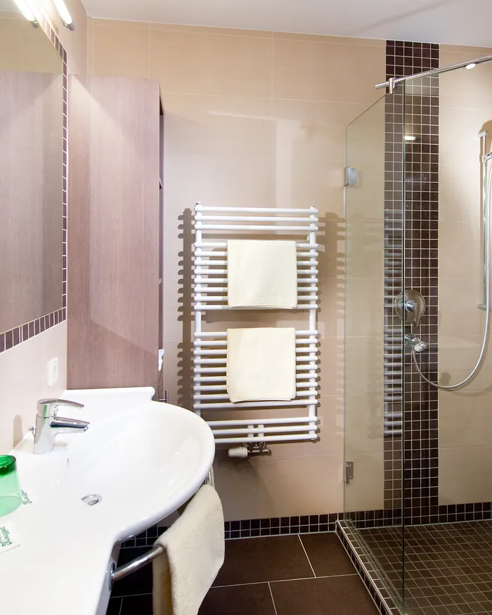 Modernes Hotelbad mit Glasdusche, Handtuchwärmer und Keramikwaschbecken