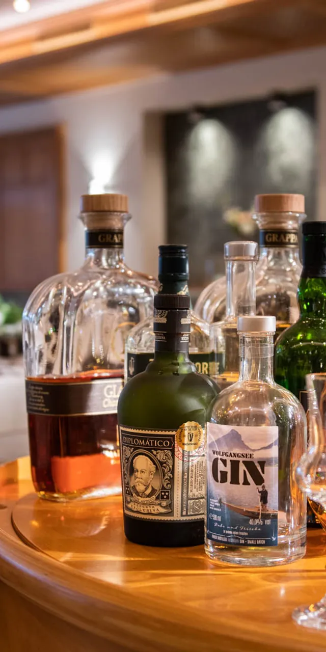Verschiedene Spirituosenflaschen und Cocktailgläser auf einem Servierwagen in einem gehobenen Restaurant