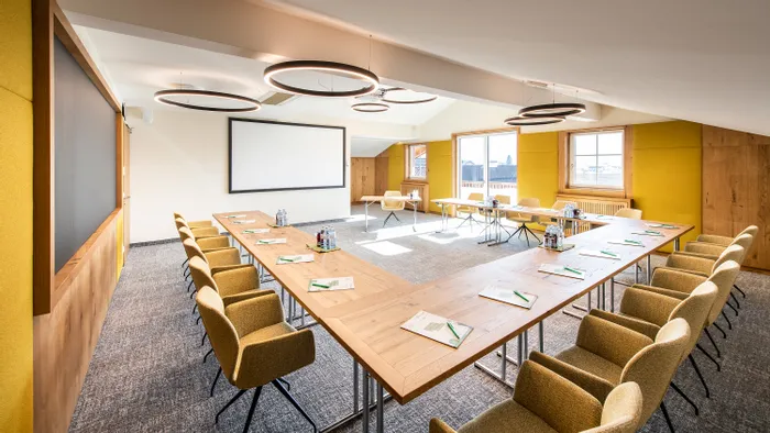 Modern conference room with U-shaped wooden table, yellow chairs, and large windows