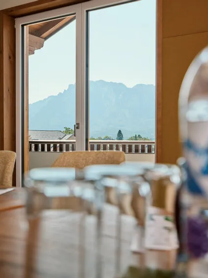 Bergblick durch Glastür in einem modernen Konferenzraum mit Holzelementen