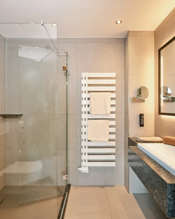 Modern hotel bathroom with walk-in shower, large mirror and granite countertop sink