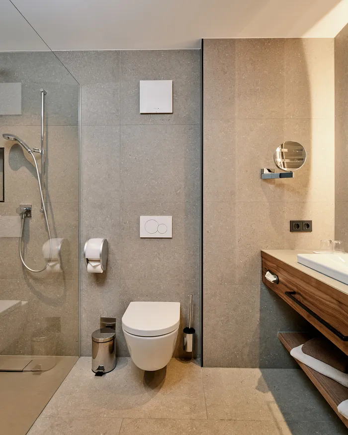 Bagno moderno d'hotel con doccia walk-in, WC sospeso e mobile lavabo in legno