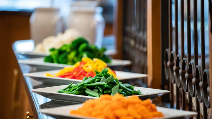 Colorful fresh vegetables neatly arranged on white buffet platters