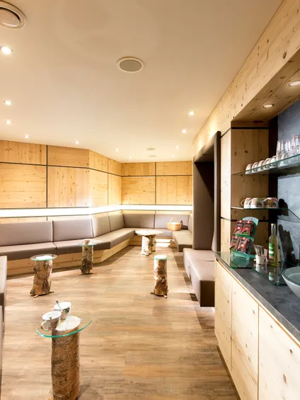Moderne Wellness-Lounge mit Holzwänden, gemütlichen Sitzbereichen und Erfrischungsecke