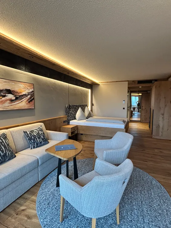 Modernes Hotelzimmer mit Doppelbett, Sofa, Sesseln, Holzboden und Ambientebeleuchtung